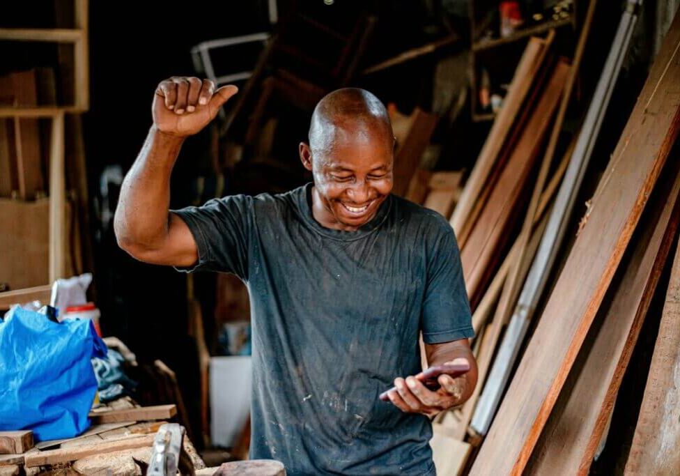 small business owner-woodshop-happy-phone-CRA small business owner-woodshop-happy-phone-CRA